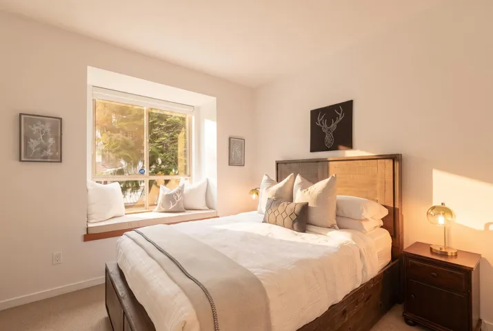 Window bench seating with a wood sill, framed by white walls and neutral carpeting
