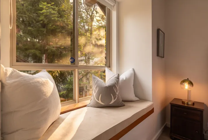 Window seating with a wood sill and cushioned bench, featuring a large multi-pane window, neutral wall tones, and wood-finish flooring