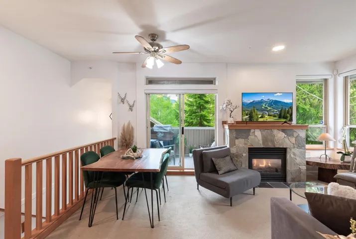 Living area featuring a stone-clad fireplace with a wood mantel, sliding glass door to a balcony, and multiple windows
