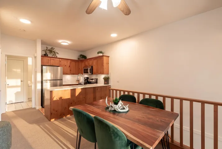 Kitchen and dining area featuring wood-finish cabinetry, stainless steel appliances, a white subway tile backsplash, and recessed lighting
