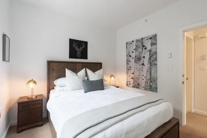 White walls provide a neutral backdrop for a bed featuring a wood-finish headboard and frame