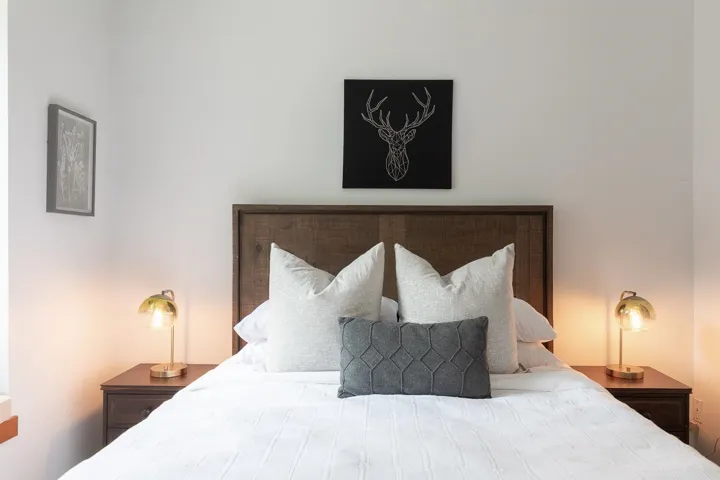 Bedroom featuring a wood-finish headboard, white walls, and matching wood-finish bedside tables