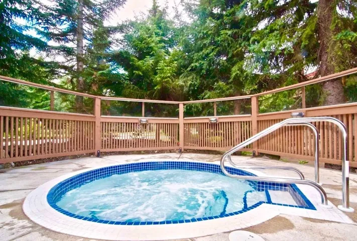 Circular hot tub with blue mosaic tile and a concrete surround