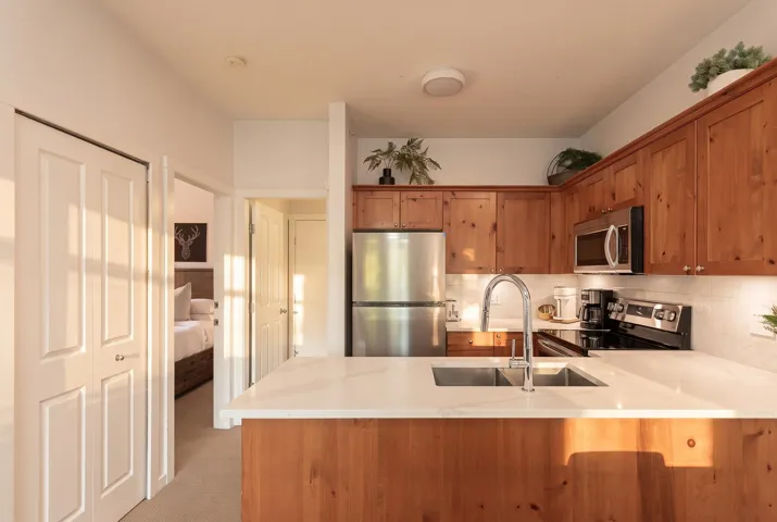 Kitchen featuring wood cabinetry, stainless steel appliances, a double basin sink, and white countertops