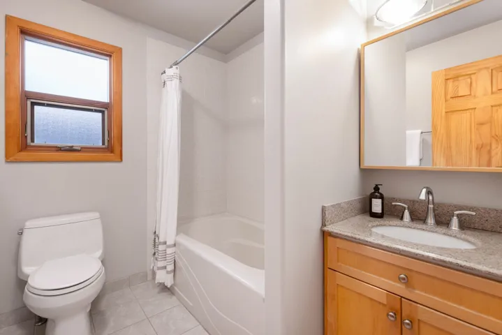 Full bath featuring vanity, shower / bath combo with shower curtain, and light tile patterned flooring