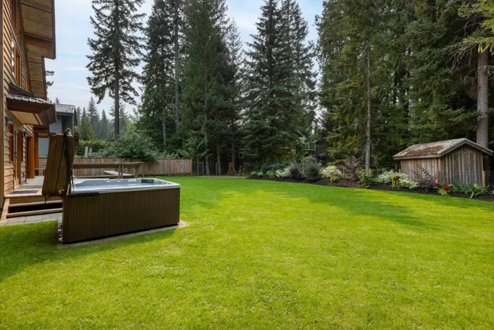 View of yard featuring a deck, a hot tub, and view of wooded area
