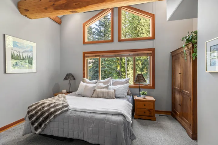 Carpeted bedroom featuring beamed ceiling and a high ceiling