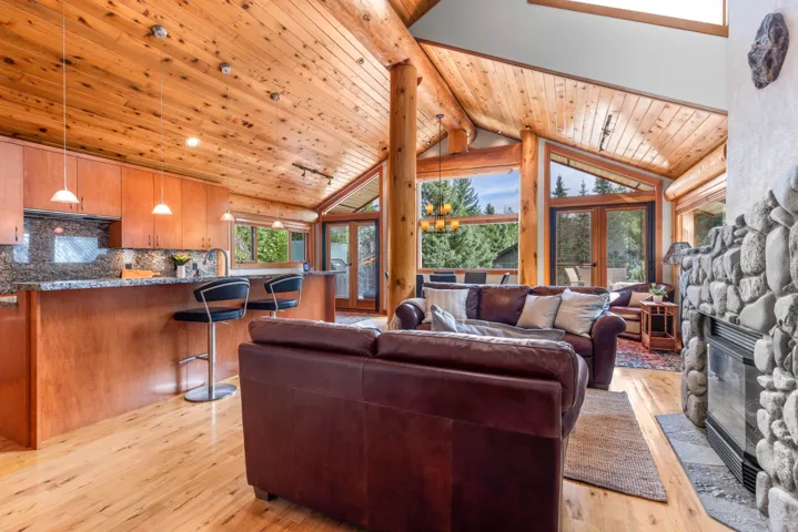 Living room with light wood-style floors, high vaulted ceiling, a fireplace, a wooden ceiling with exposed beams, and french doors