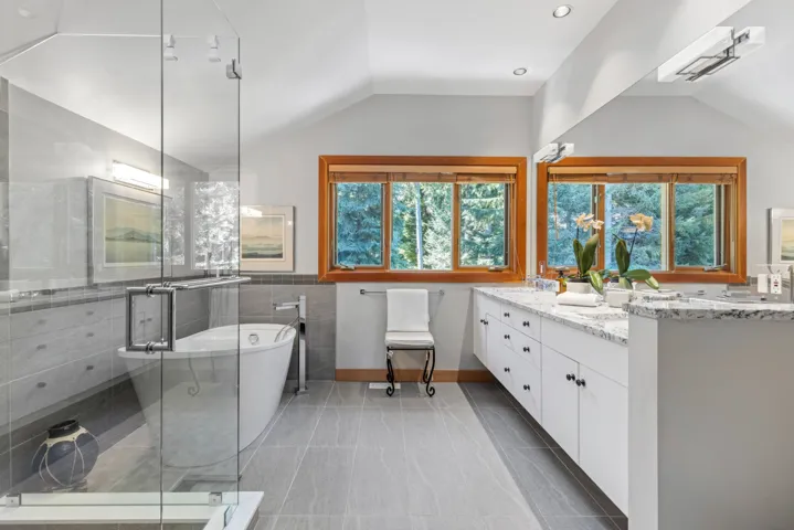 Full bath featuring lofted ceiling, double vanity, a shower stall, a freestanding bath, and light tile patterned flooring