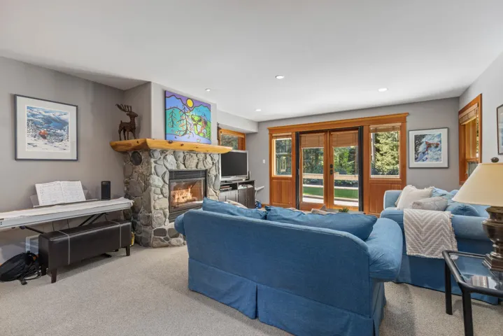 Living area with carpet flooring, a stone fireplace, and recessed lighting