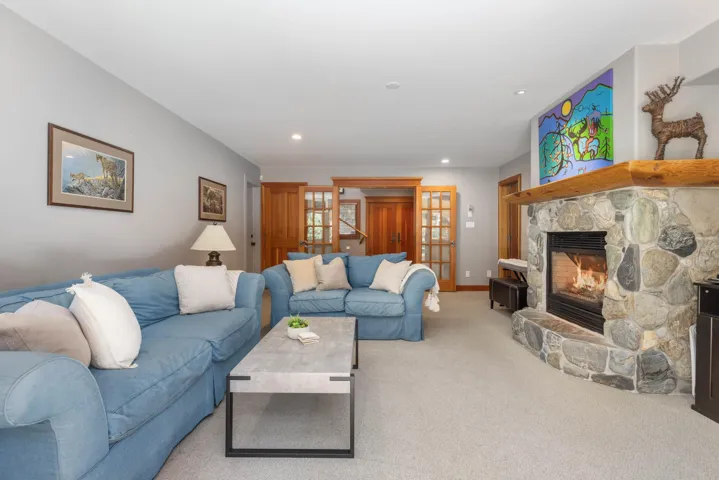 Carpeted living room with a stone fireplace and recessed lighting