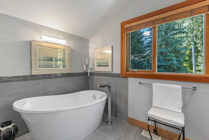 Bathroom featuring a freestanding tub, tile patterned floors, tile walls, and lofted ceiling