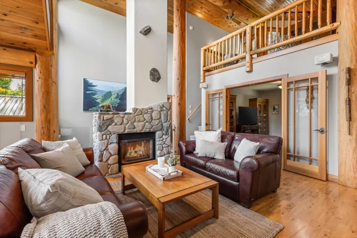 Living room with a fireplace, a high ceiling, wood finished floors, stairs, and a wood ceiling with exposed beams