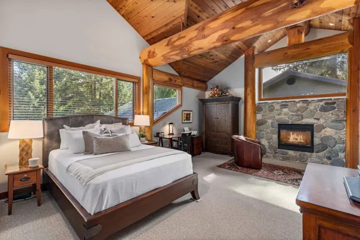 Bedroom featuring carpet, high vaulted ceiling, a wooden ceiling with exposed beams, and a stone fireplace