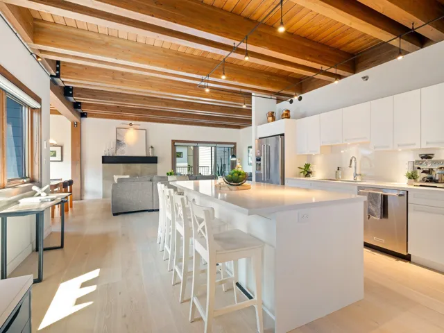 Kitchen with stainless steel appliances, a wooden ceiling with exposed beams, a breakfast bar area, light wood finished floors, and white cabinets