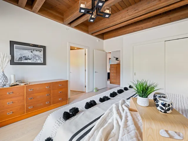 Bedroom featuring a wooden ceiling with exposed beams, light wood-style floors, ensuite bath, and a closet