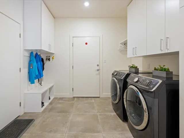 Laundry area with separate washer and dryer, cabinet space, and light tile patterned floors