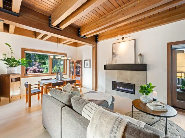 Living area with plenty of natural light, a wood ceiling with exposed beams, light wood-style floors, and a fireplace