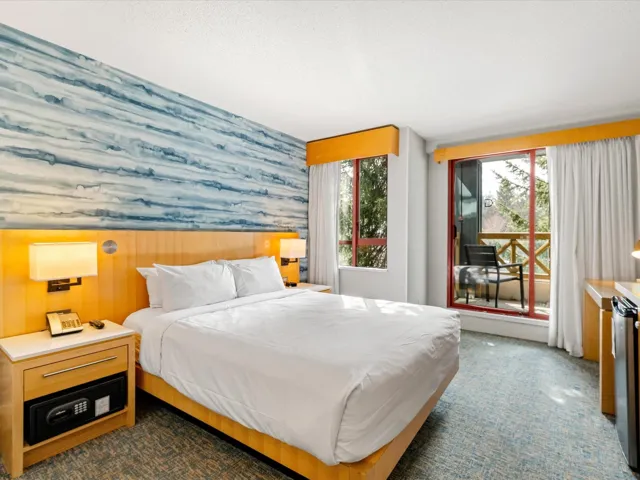 Carpeted bedroom with a wainscoted wall, a textured ceiling, wallpapered walls, and access to outside