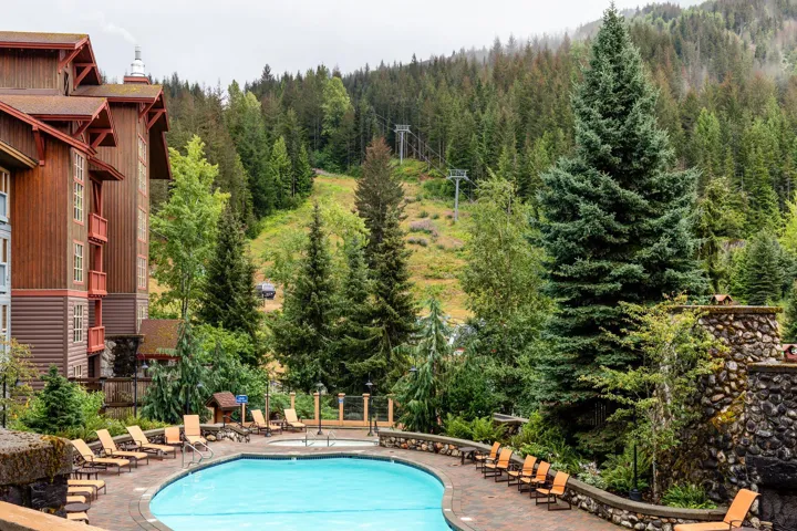 Resort-style pool area featuring a curved swimming pool, integrated spa, and expansive paver deck