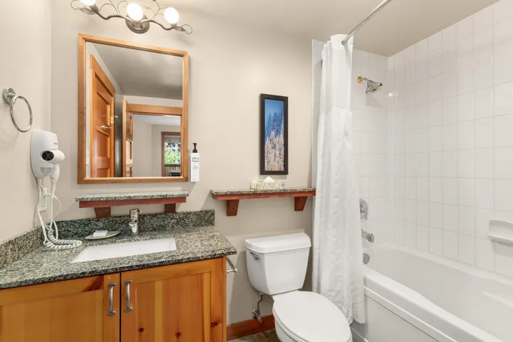 Bathroom featuring a wood-finish vanity with dual-door cabinetry, a speckled countertop, and an integrated sink