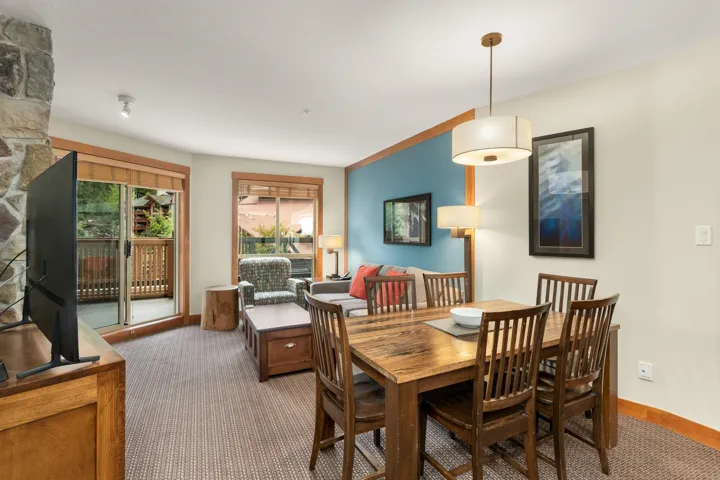 Open-concept living area featuring a stone accent wall, wood-finish flooring, and a sliding glass door opening to an outdoor balcony