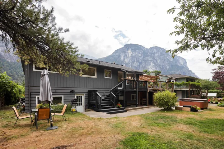 Rear view of property featuring a hot tub, stairway, a deck with mountain view, and a yard