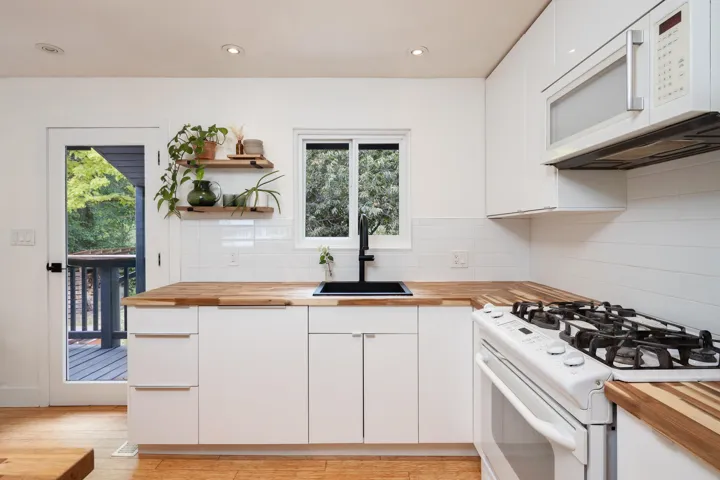 Kitchen featuring wood counters, white appliances, tasteful backsplash, white cabinets, and recessed lighting