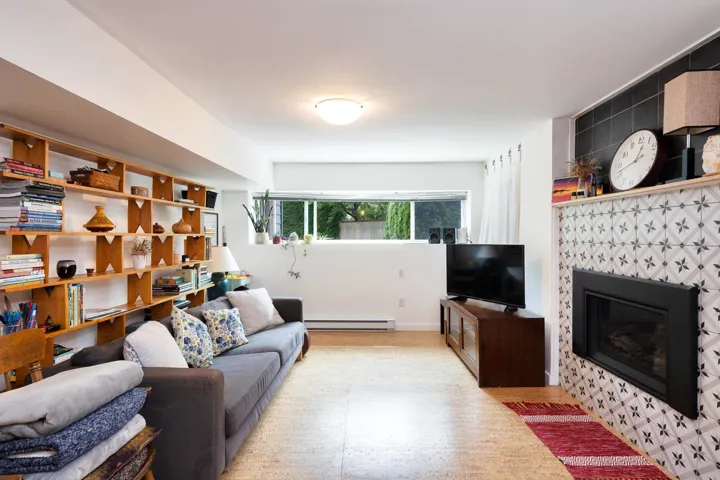 Living area with a tiled fireplace and a baseboard heating unit