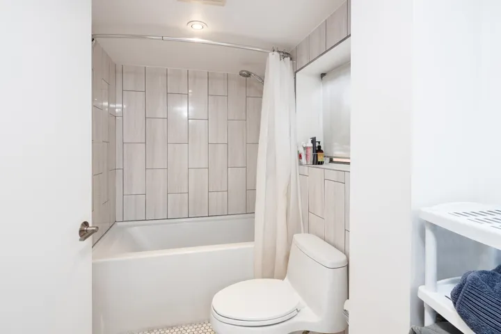 Bathroom featuring toilet and shower / bath combination with curtain