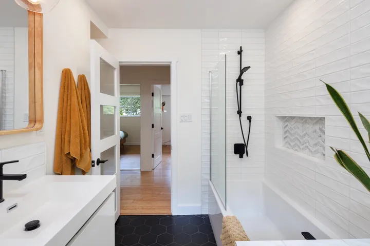 Bathroom featuring a tile shower, vanity, and tile patterned flooring