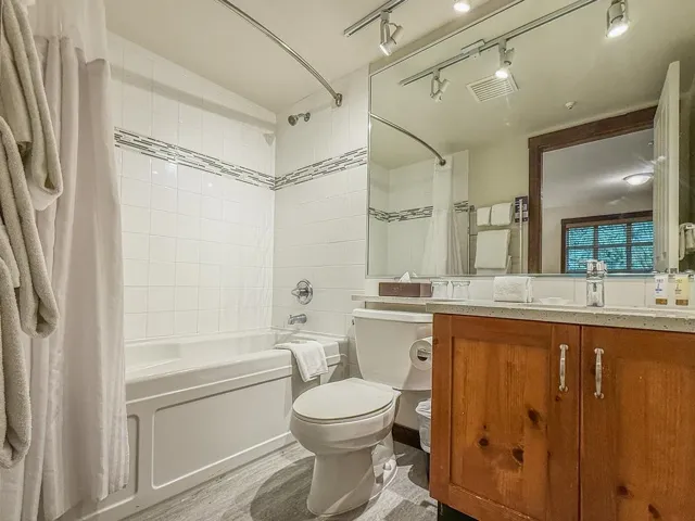 Full bath with shower / bath combination with curtain, vanity, light wood-style flooring, and rail lighting