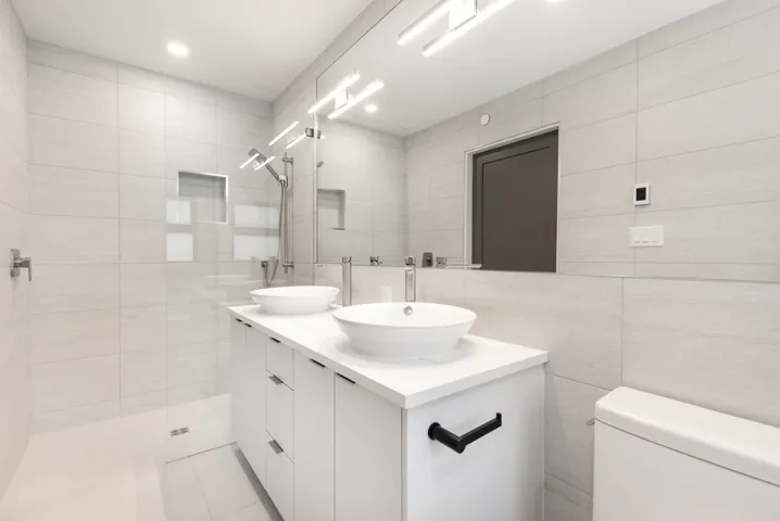 Bathroom with double vanity, tile walls, and a walk in shower