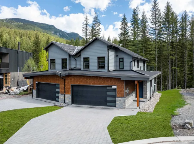 View of front of home with stone siding, decorative driveway, an attached garage, and a front yard