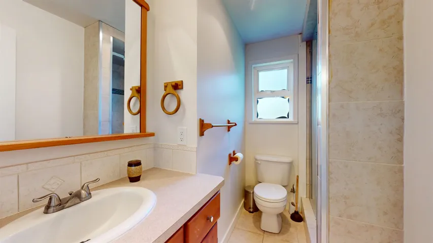 Bathroom featuring vanity, tile patterned floors, toilet, an enclosed shower, and baseboards