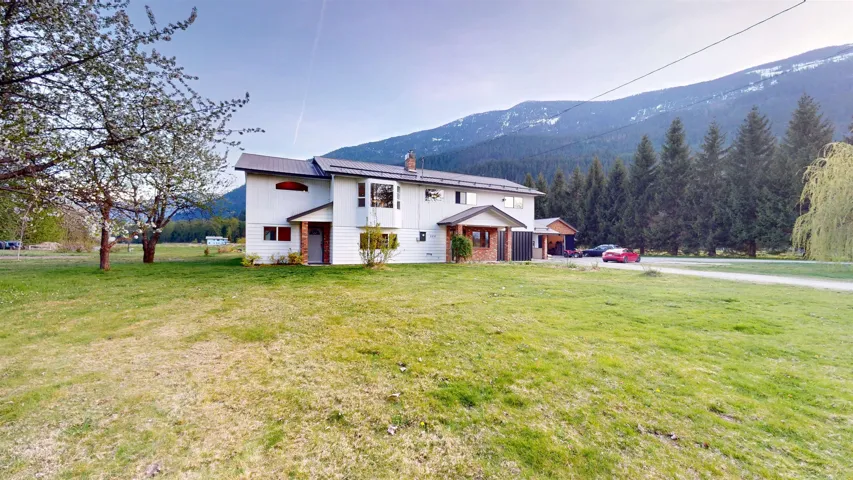 Exterior space featuring board and batten siding, a chimney, a front yard, a mountain view, and a forest view