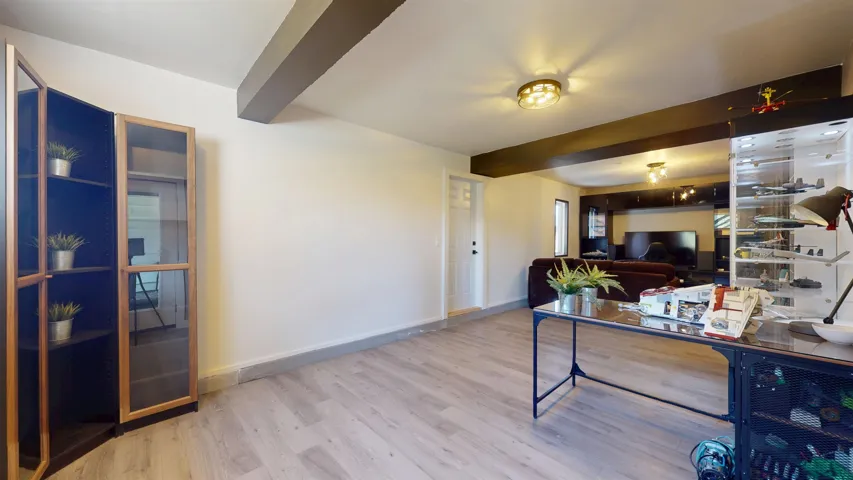 Home office with baseboards, beamed ceiling, and wood finished floors
