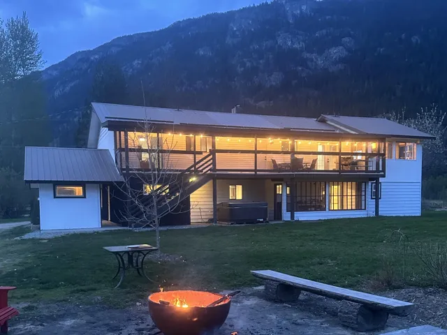 Back of property with stairs, a jacuzzi, metal roof, a deck with mountain view, and a yard
