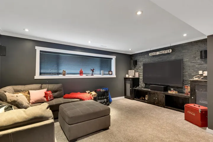 Carpeted recreation room featuring dark gray walls, a white ceiling with recessed lighting, and a window with white trim and horizontal blinds