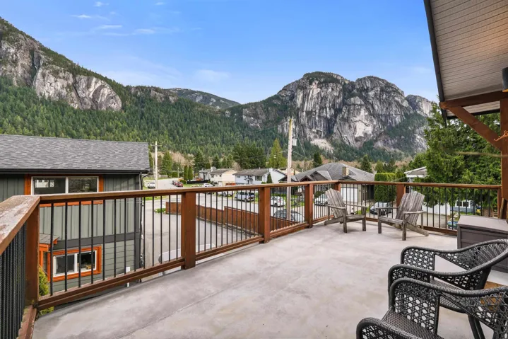 Spacious outdoor deck with concrete surface and a wood railing featuring black balusters