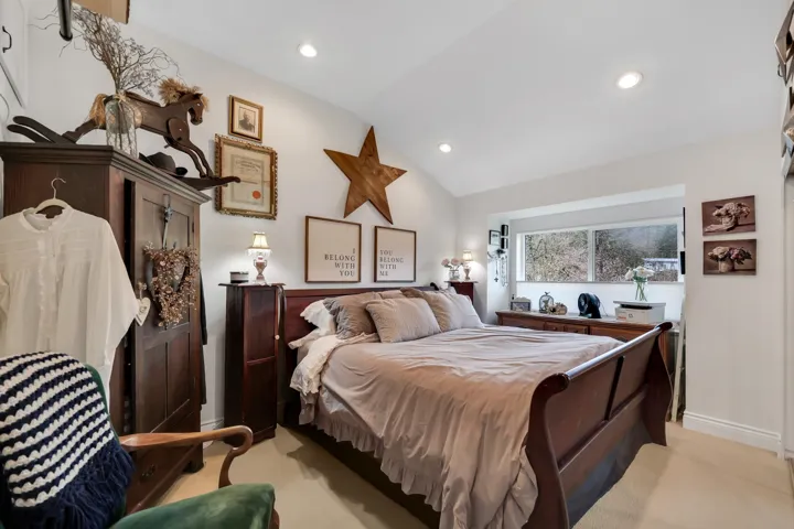 Bedroom featuring a vaulted ceiling with recessed lighting, an integrated window seat, and wood-finish flooring