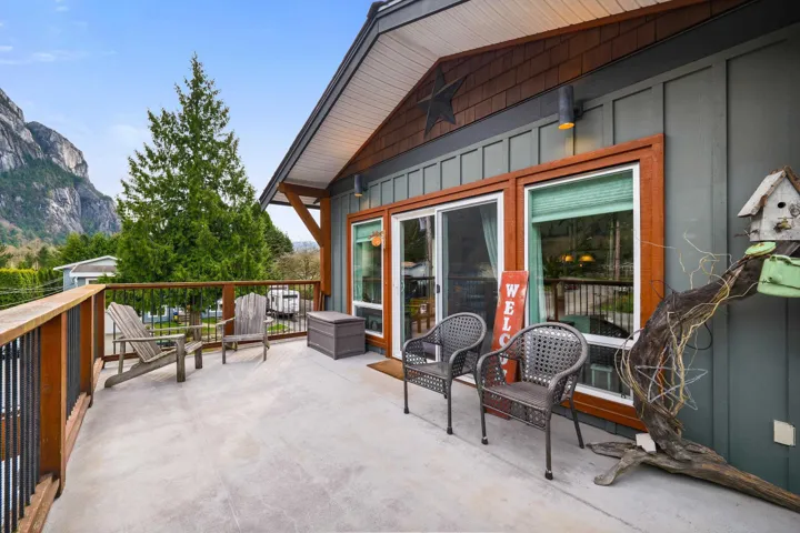 Expansive outdoor deck featuring a concrete surface, wood railing with metal balusters, and direct access to interior spaces through a sliding glass door