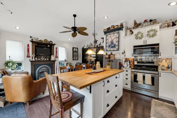 Spacious kitchen featuring white cabinetry, a wood-top island with seating, dark wood-finish flooring, and stainless steel appliances