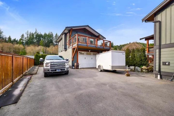 Multi-level residence featuring a ground-level garage and an upper-level balcony with wood railings