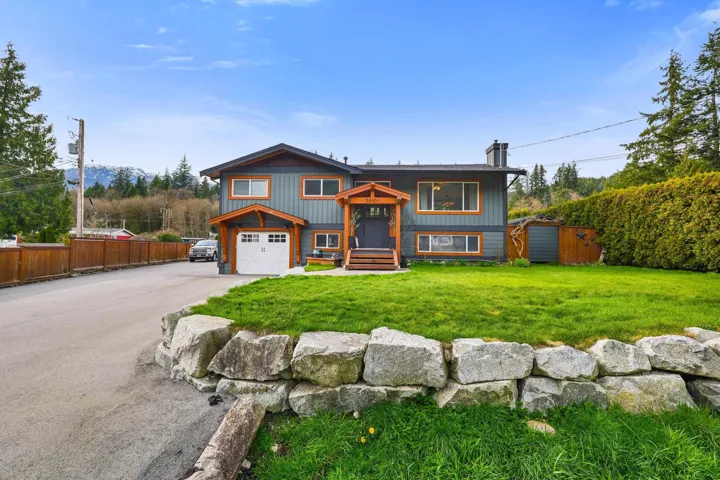 Two-story residence featuring a gray exterior with wood trim accents, an attached single-car garage, and a covered front entry
