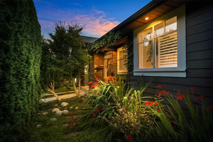 Exterior featuring dark horizontal siding, white window trim, and a prominent window with louvered shutters