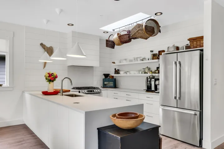 Kitchen featuring a stainless steel undermount sink, gooseneck faucet, white countertops, and shiplap accent wall