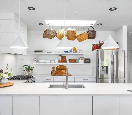 Contemporary kitchen featuring an expansive white island with integrated sink, stainless steel appliances, and wood-finish flooring