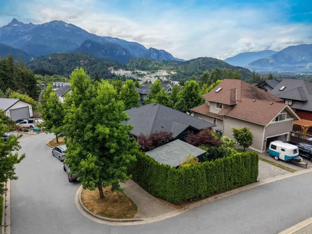 Residential property featuring a paved driveway, attached garage, and mature perimeter hedging
