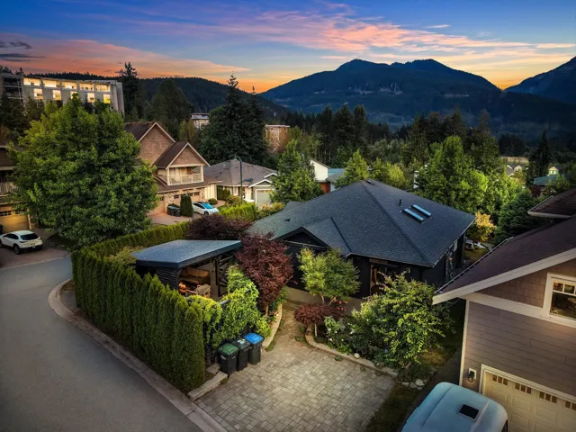 Paved driveway leading to a modern home with a dark-pitched roof, featuring skylights